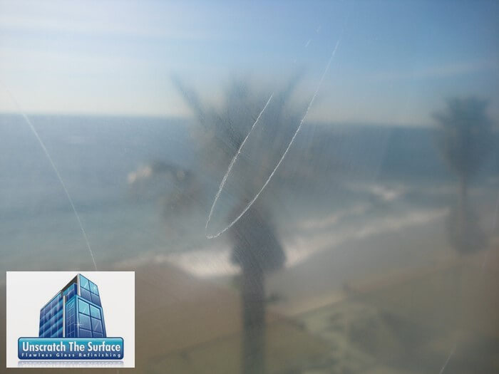 Closeup view of glass graffiti deep scratch with ocean view behind. At Laguna Beach, CA